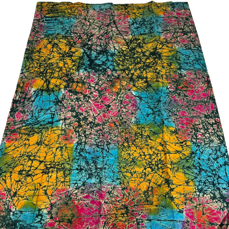 Puede incluir: Una tela colorida con un patr&oacute;n batik en tonos de azul, amarillo, rosa y negro. La tela tiene un efecto tie-dye con un dise&ntilde;o abstracto en espiral.