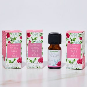 May include: Three bottles of essential oil blends, each with a pink and green label featuring a floral design and the text "Californian White Sage & Rose". The bottles are on a white surface.