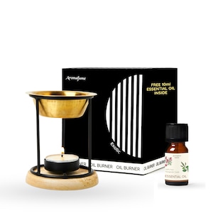 May include: A black and gold essential oil burner with a wooden base. The burner has a round, brass bowl and a black metal frame. A small tea light candle sits in the base. The burner comes with a 10 ml bottle of essential oil labeled "Exotic" and "100% Pure Therapeutic Grade Essential Oil".