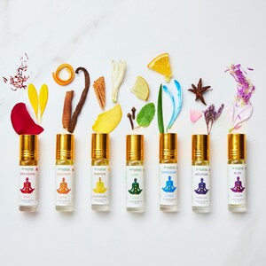 May include: Seven gold rollerball bottles with colorful labels and text that reads "Grounding", "Creativity", "Purpose", "Love", "Expression", "Intuition", and "Bliss". Each bottle has a different colored symbol and chakra name.