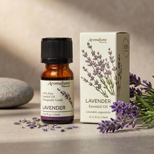 May include: A 10ml amber glass bottle of Aromafume Naturale lavender essential oil with a black cap, next to its matching cream-coloured cardboard box. The label and box feature lavender illustrations and text stating 100% Pure Essential Oil.