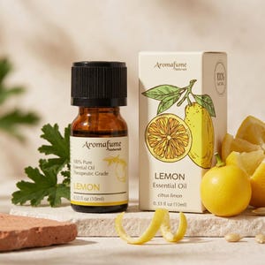 May include: Aromafume Lemon Essential Oil. A brown glass bottle and a box with a lemon illustration are displayed. The bottle contains 0.33 fl oz (10ml) of 100% pure essential oil. Fresh lemons and lemon peelings are also visible.