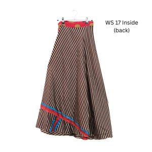 Op de afbeelding: Een lange rok met een bruin en wit diagonaal gestreept patroon, een rode tailleband met gouden cirkelvormige accenten en een decoratieve blauwe en rode bies bij de zoom. De tekst WS 17 Inside (back) is rechts in de afbeelding zichtbaar.
