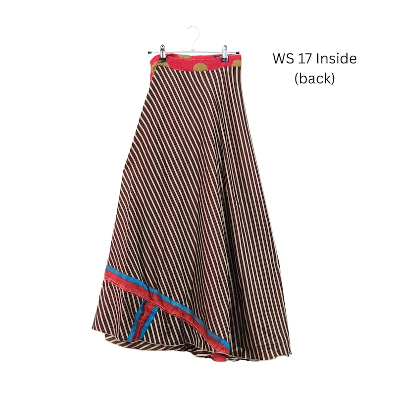 Op de afbeelding: Een lange rok met een bruin en wit diagonaal gestreept patroon, een rode tailleband met gouden cirkelvormige accenten en een decoratieve blauwe en rode bies bij de zoom. De tekst WS 17 Inside (back) is rechts in de afbeelding zichtbaar.