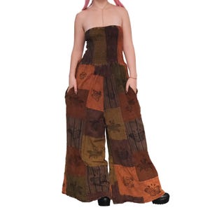May include: A strapless jumpsuit featuring a smocked bodice and wide-leg trousers. The garment is constructed from a patchwork of brown, olive green, and orange fabric panels, each decorated with black butterfly prints and side pockets.