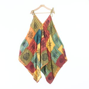 May include: A sleeveless dress featuring a patchwork design with various colored panels in shades of orange, yellow, green, red, and blue. The fabric is printed with black ink motifs including suns, flowers, and hamsa hand symbols.