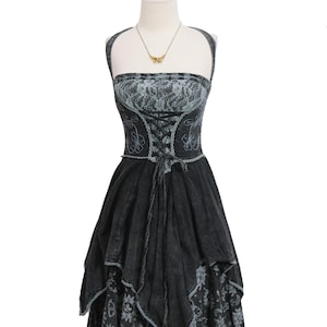May include: A black and grey halter dress featuring a lace-up corset-style bodice with floral embroidery. The dress has a layered, uneven hemline and a fitted waist, displayed on a mannequin with a gold-toned necklace featuring a butterfly pendant.
