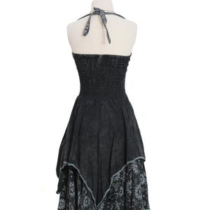 May include: A black halter dress with a smocked bodice and a tie-neck closure. The skirt features an uneven hemline with a distressed wash finish. The lower portion of the skirt displays a repeating pattern of white suns, moons, and stars on black fabric.