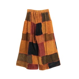 May include: Wide-leg pants featuring a patchwork design with various rectangular fabric panels in shades of orange, brown, dark red, and black. The garment has an elasticized waistband and two large patch pockets on the back.