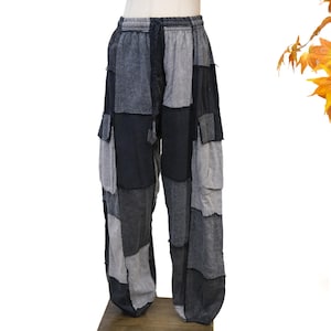 May include: Patchwork trousers featuring a color palette of charcoal, slate gray, and black. These pants have an elasticized waistband with a drawstring, multiple rectangular cargo-style pockets on the legs, and a loose, relaxed fit throughout.