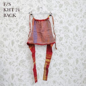 May include: A sleeveless halter top featuring a patchwork of orange, purple, and red fabric with visible kantha-style stitching. The garment includes long tie straps at the neck and waist, with the text F/S KHT 24 BACK printed in the upper left corner.