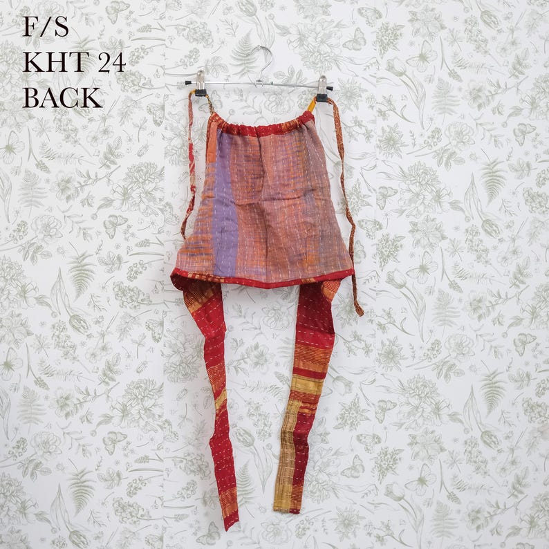 May include: A sleeveless halter top featuring a patchwork of orange, purple, and red fabric with visible kantha-style stitching. The garment includes long tie straps at the neck and waist, with the text F/S KHT 24 BACK printed in the upper left corner.