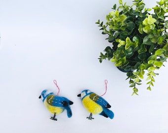 May include: Two bluebird ornaments made of felt with yellow bellies and red string hangers.