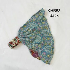May include: A teal fabric headband with a floral pattern and white stitching, featuring a gathered design and a contrasting red and white patterned elastic strap. The text KHB53 Back is printed in black in the upper right corner of the image.