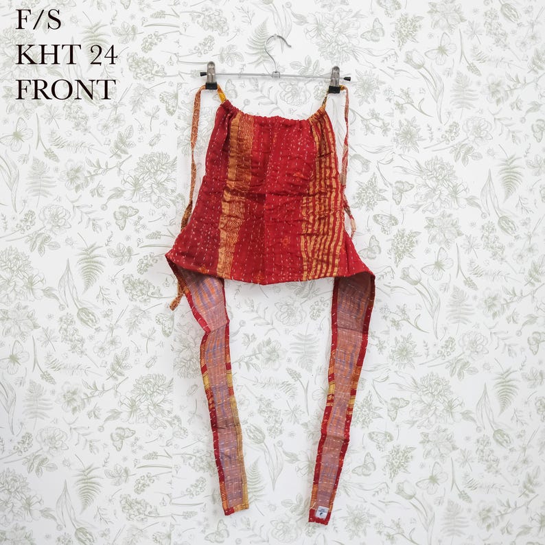 May include: A red and gold patterned halter top featuring a gathered neckline and long fabric ties. The garment displays a textured, stitched appearance with vertical stripes and includes the text F/S KHT 24 FRONT printed in the upper left corner.