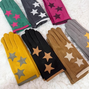 May include: A collection of seven pairs of gloves in various colors including green, dark gray, magenta, yellow, black, tan, and light gray. Each pair features three star-shaped patches on the back of the hand, with contrasting trim at the wrist.