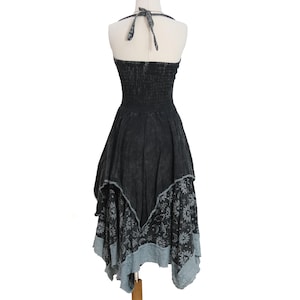 May include: A black halter dress with a smocked bodice and a tie-neck closure. The skirt features an asymmetrical handkerchief hemline with a layered design, showcasing a grey celestial print of suns, moons, and stars on the lower panel.