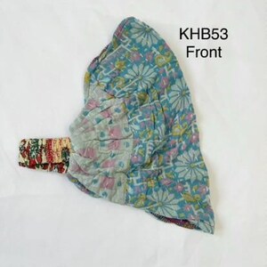 May include: A fabric headband labeled KHB53 Front, featuring a teal base with a white and pink floral pattern. The band includes a gathered section and a contrasting strap with a red, green, and white intricate print, showcasing visible stitching.