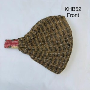 May include: A brown fabric headband featuring a repeating black wave pattern and white stitched detailing. The elastic band section displays a multi-colored floral print. The text KHB52 Front is visible in the upper right corner of the image.