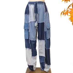 Puede incluir: Pantalones cargo de mezclilla tipo patchwork con una mezcla de cuadrados de tela en tonos azul claro, medio y oscuro con bordes deshilachados. Estos pantalones holgados incluyen una cintura elástica con cordón y bolsillos cargo laterales.