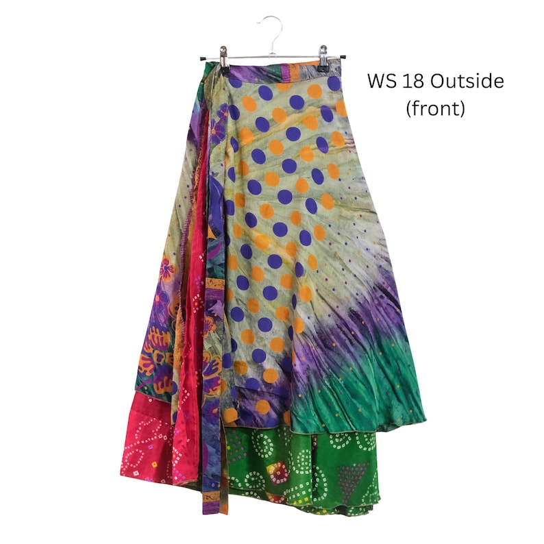 Op de afbeelding: Een wikkelrok met een veelkleurig patroon met paarse stippen op een lichte achtergrond, overgaand in groene, roze en paarse bloemen- en geometrische secties. De tekst WS 18 Outside (front) is zichtbaar aan de rechterbovenkant van de afbeelding.