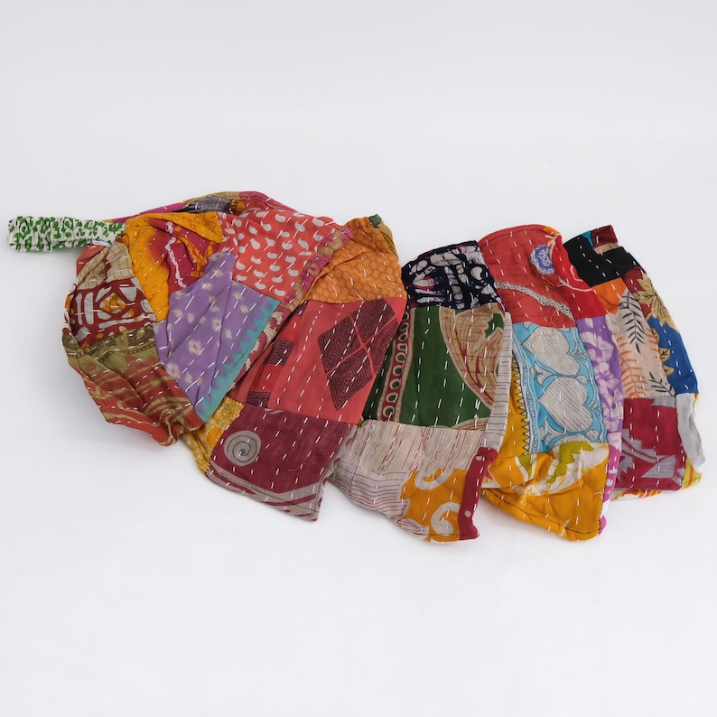 May include: A collection of fabric pouches made from multicolored patchwork textile scraps featuring various patterns including floral, geometric, and heart motifs. Each pouch is constructed with visible white running stitch quilting.