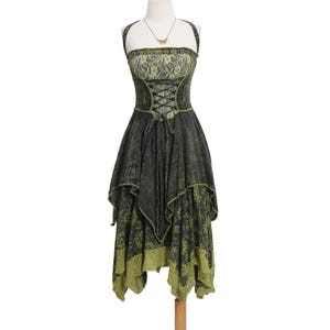 May include: A sleeveless dress featuring a dark charcoal and olive green color palette. The bodice includes a lace overlay and a central corset-style lace-up detail. The skirt has an asymmetrical handkerchief hem with a floral pattern and lace trim.