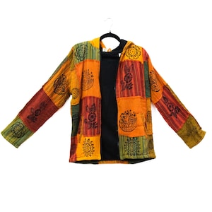 Può includere: Una giacca con cappuccio e cerniera a maniche lunghe con un design patchwork di pannelli in tessuto arancione, giallo, verde e rosso. La giacca è decorata con motivi floreali neri e circolari a forma di sole e ha una fodera interna nera.
