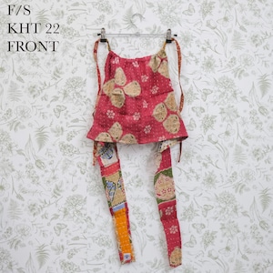 May include: A sleeveless halter top featuring a vibrant pink base with a multi-colored floral and geometric pattern. The garment includes long fabric ties at the neck and waist, with visible stitching throughout. Text F/S KHT 22 FRONT is present.
