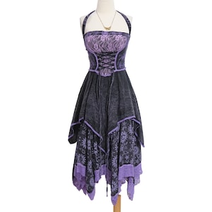 May include: A halter-style dress featuring a black and purple color scheme. The bodice includes a lace overlay and a corset-style lace-up front. The skirt has an asymmetrical handkerchief hemline with a celestial sun and moon print pattern.