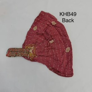 May include: A dusty rose fabric headwrap featuring white dashed vertical stitching and small floral patterns. The accessory includes a multi-colored patterned elastic band at the side. The text KHB49 Back is printed in black in the upper right corner.