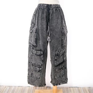 May include: Wide-leg cargo trousers in a dark grey acid-wash finish. These trousers feature an elasticated waistband with a drawstring, two large side cargo pockets on each leg, and two additional smaller pockets positioned below the main cargo pockets.