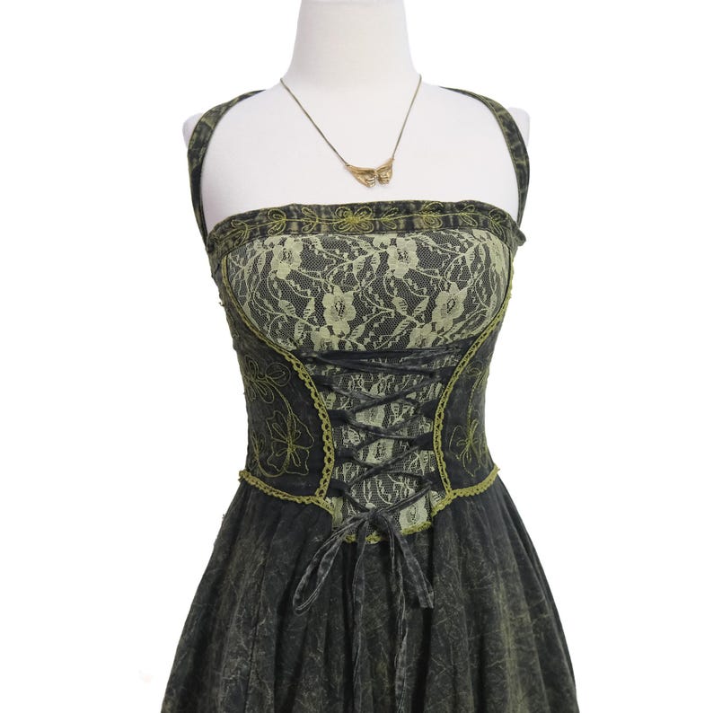 May include: A sleeveless dress featuring a dark charcoal gray acid-wash fabric with lime green lace overlay on the bodice. The front includes a black lace-up corset-style closure with lime green trim and a gold-toned butterfly pendant necklace.
