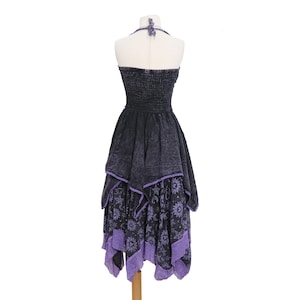 May include: A black and purple halter dress featuring a smocked bodice and a layered handkerchief hemline. The skirt displays a celestial print with suns, moons, and stars, finished with a purple lace trim along the bottom edges of the fabric.