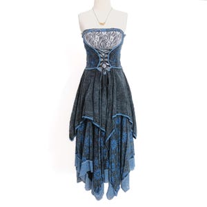 May include: A strapless dress featuring a dark charcoal acid-wash denim bodice with a white lace panel at the chest and a black lace-up corset detail. The skirt is layered with a dark floral print and a light blue hem with lace trim accents.