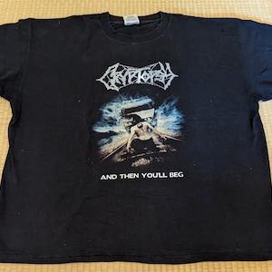 May include: Black t-shirt with a white graphic of a band called "Cryptopsy" and the text "And Then You'll Beg".