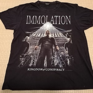 May include: Black t-shirt with a graphic print of a band called "Immolation" and the text "Kingdom of Conspiracy".