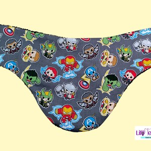 Peut inclure: Article en tissu gris avec un motif de super-héros de dessins animés, dont Iron Man, Captain America et Thor. L'article a une forme incurvée et une bordure noire. Le coin inférieur droit porte le logo "Life Telitas".