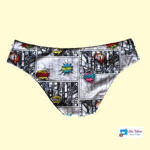 Peut inclure: Sous-vêtements noir et blanc avec un imprimé de bande dessinée mettant en vedette des bulles de dialogue colorées avec des mots comme "Hey", "Smile", "Boom", "Wow", et "Oops!" Les sous-vêtements sont fabriqués par Lilo Telitas Hand Made.