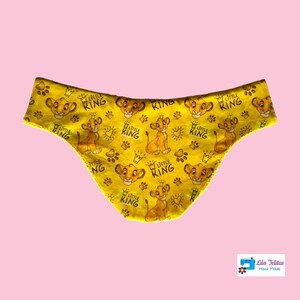 Peut inclure: Tissu jaune avec un motif répété d'un lionceau de dessin animé avec les mots "Little King" et une couronne. Le tissu est en forme de couvre-couche.