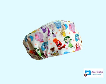 Può includere: Un berretto da scrub in tessuto bianco con una stampa colorata di personaggi del film Inside Out. Il berretto ha un fiore rosa e il testo "Lilo Telitas Hand Made".