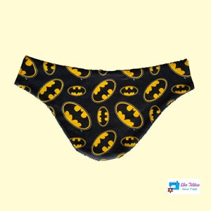 Peut inclure: Bavoir en tissu noir et jaune avec un motif répété du logo Batman. Le bavoir est fait main et a un bord effiloché.