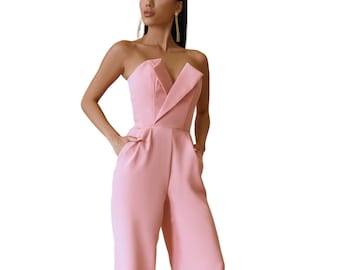 May include: A pink strapless jumpsuit with a wide leg and a sharp, angular neckline. The jumpsuit is made of a smooth, silky fabric.
