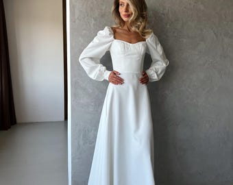 Abito midi bianco con maniche voluminose e scollo a cuore, ideale per le prove del matrimonio o per una fuga d'amore.