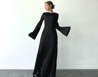 May include: A long, black dress with flared sleeves. The dress has a simple, elegant design with a fitted bodice and a flowing skirt. The sleeves are long and bell-shaped, adding a dramatic flair to the garment.