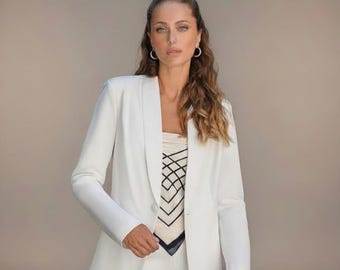 Completo pantalone bianco a due pezzi con blazer monopetto e pantaloni a zampa.