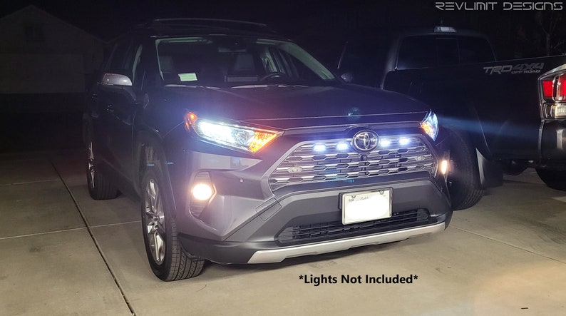 May include: A black SUV with a chrome grille and a silver bumper. The car has a license plate that is partially obscured. The car is parked in a driveway at night. The text "*Lights Not Included*" is visible at the bottom of the image.
