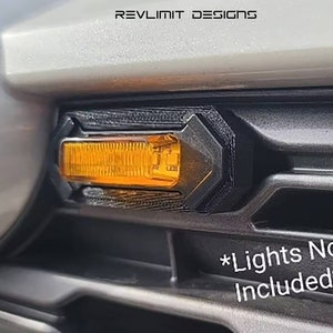 May include: A black plastic car part with an orange light. The part is designed to fit on a car's front bumper. The text "*Lights Not Included*" is printed on the car's bumper.