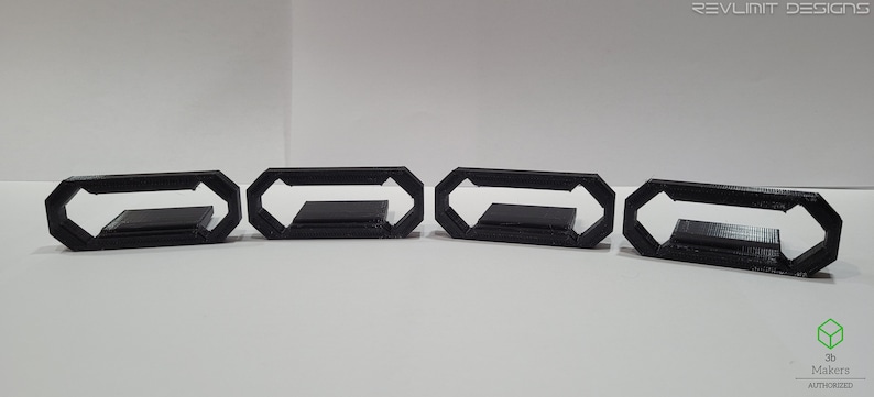 May include: Five black plastic 3D printed octagonal rings with a rectangular opening in the center.
