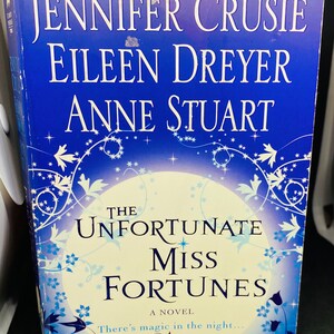 May include: Book cover with a blue background and a white moon. The title is "The Unfortunate Miss Fortunes" with the text "A Novel" below. The authors are Jennifer Crusie, Eileen Dreyer, and Anne Stuart.